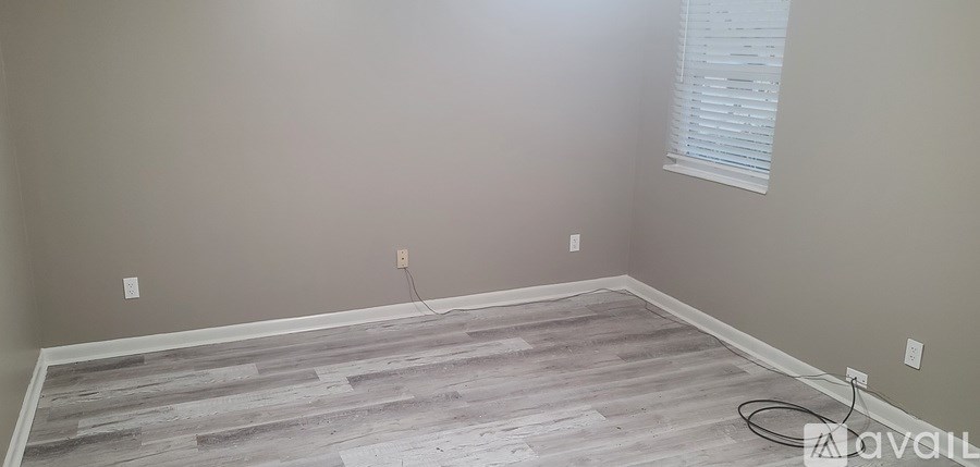 A room with wooden flooring and a window with blinds.