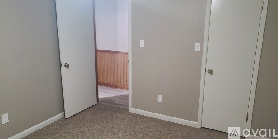 A room with three doors and a carpeted floor.