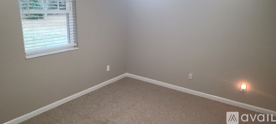 A room with a window and a carpeted floor.