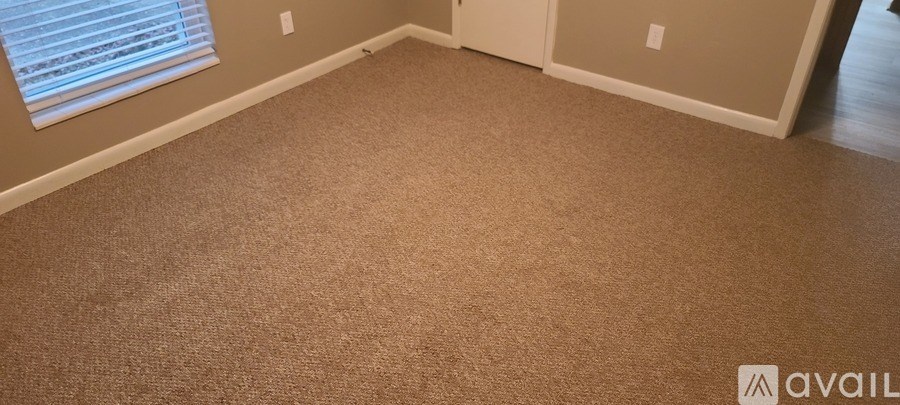 A room with a carpeted floor and a window with blinds.