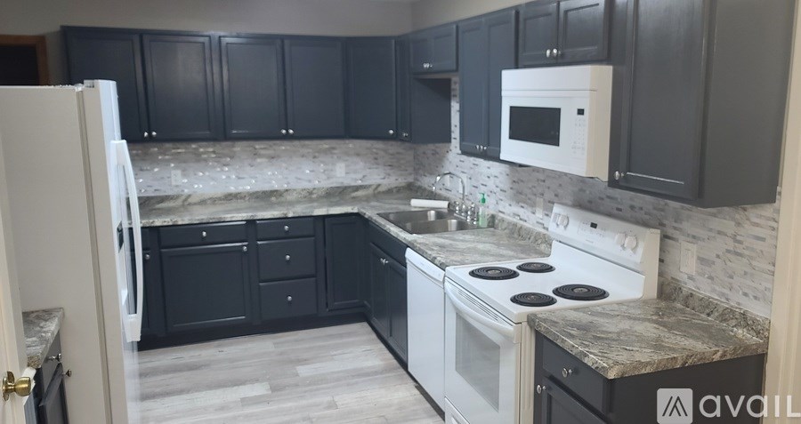 A kitchen with black cabinets and a white stove top oven.