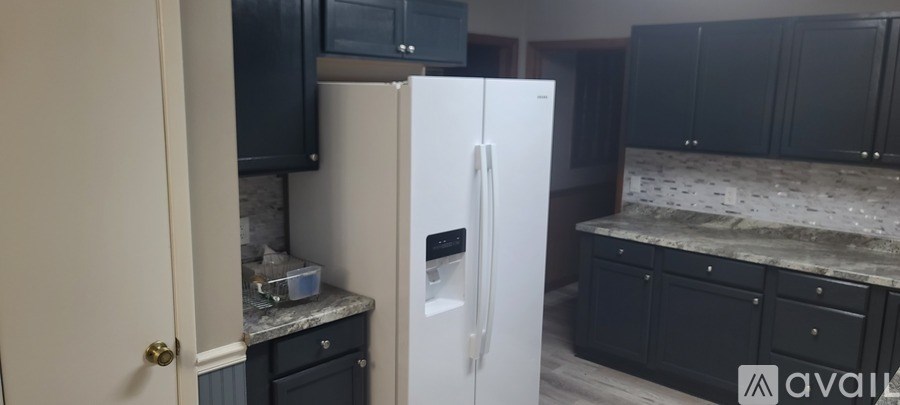 A kitchen with a white refrigerator and black cabinets.