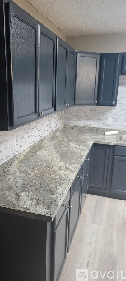 A kitchen with dark cabinets and a marble countertop.