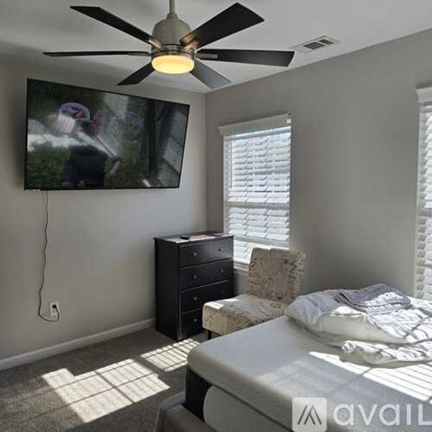 A bedroom with a bed, dresser, and a ceiling fan with a light.