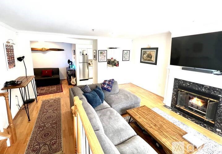 A living room with a grey couch and a fireplace.