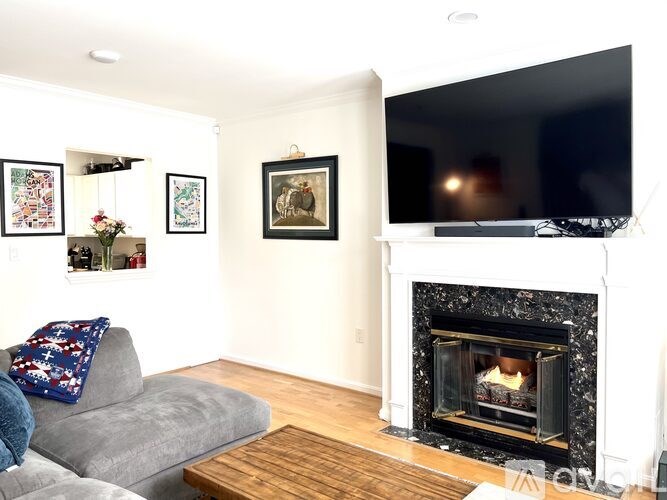 A living room with a grey couch, a fireplace, and a television.