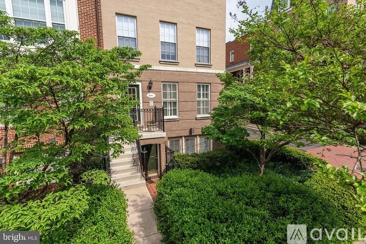 A building with a balcony surrounded by green bushes.