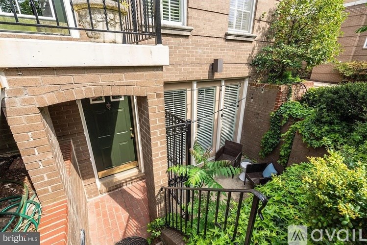 A balcony with a table and chairs overlooks a brick building.