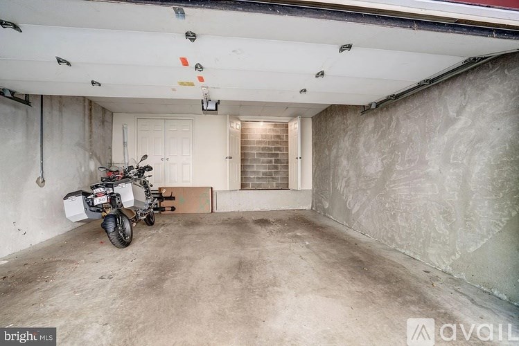 A motorcycle is parked in a garage with a white door and a brick wall.