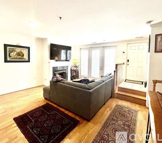 A living room with a grey couch and a fireplace.