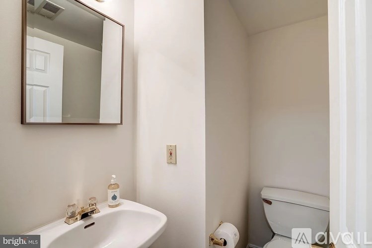 A white bathroom with a sink, mirror, and toilet.