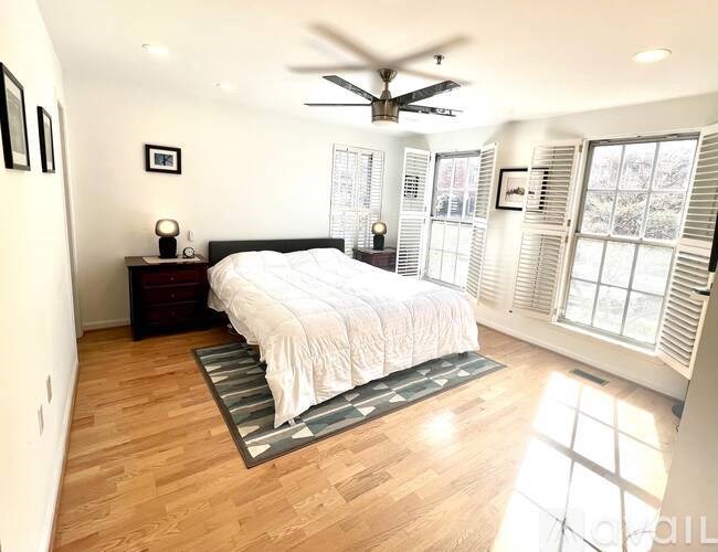 A bedroom with a bed, a ceiling fan, and a window with blinds.