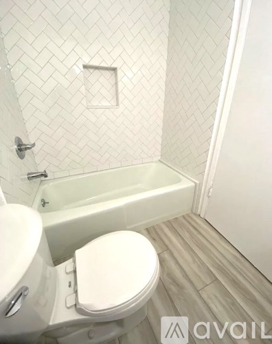 A white toilet in a bathroom with a white tiled wall.