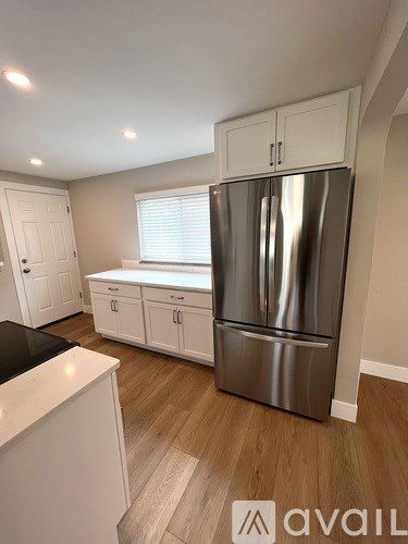 A kitchen with a stainless steel refrigerator and white cabinets.