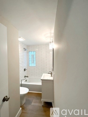 A white bathroom with a tub, toilet and sink.
