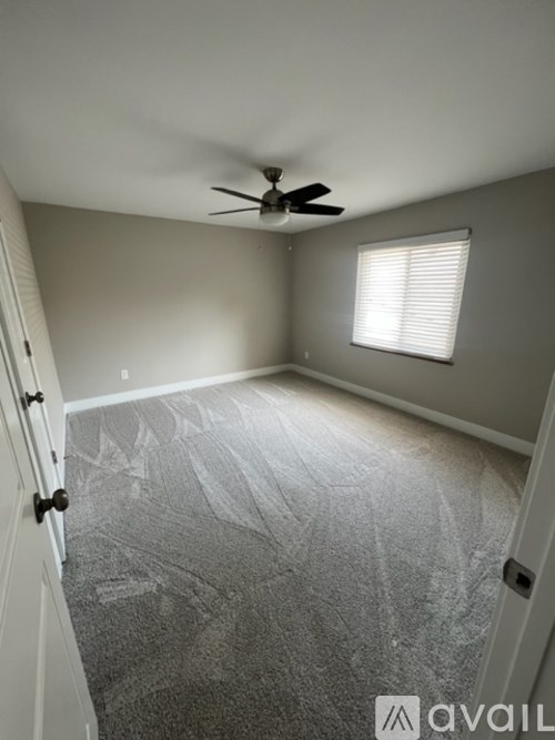 A room with a ceiling fan and a window with blinds.