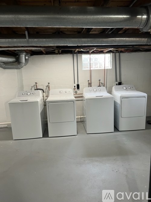 Four white washing machines are lined up in a row.