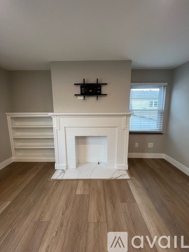 A living room with a fireplace and wooden floors.