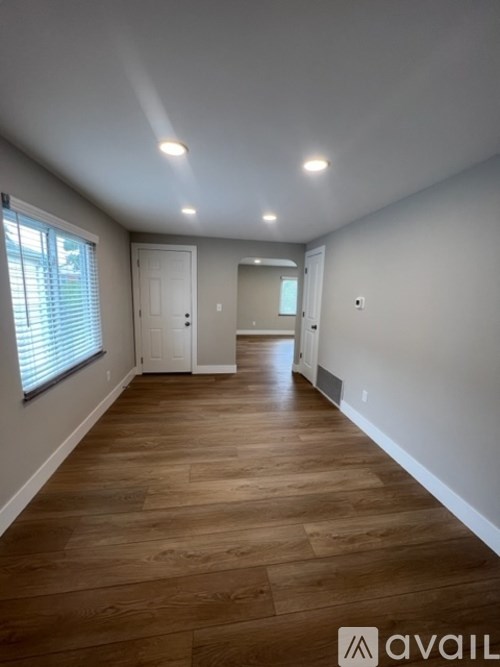 A spacious room with wooden flooring and white walls.