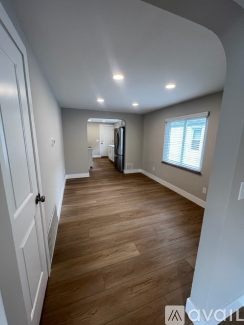 A long hallway with wood floors and white walls.