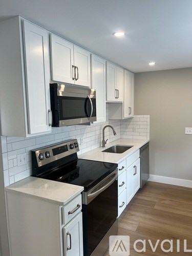 A kitchen with white cabinets and black appliances.