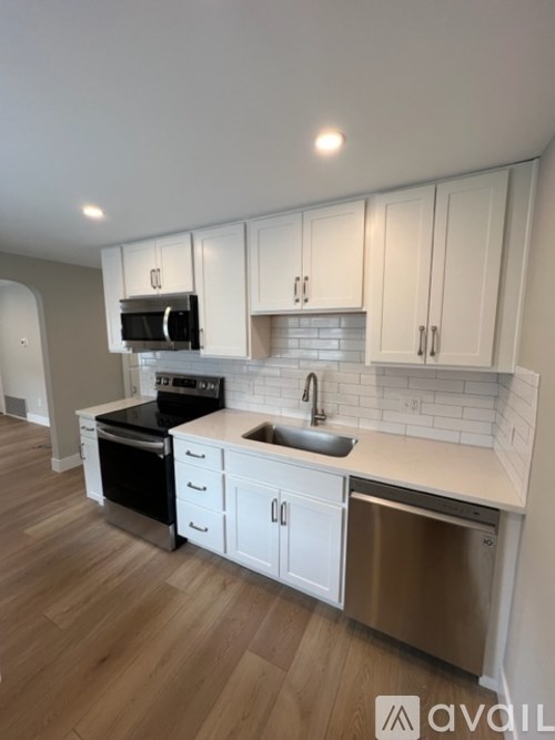 A kitchen with white cabinets and a wooden floor.