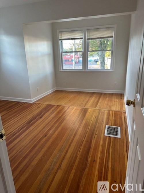 A room with wooden flooring and a window showing a street view.