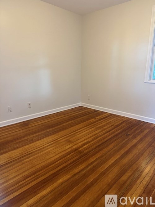 A room with wooden flooring and a window on the wall.