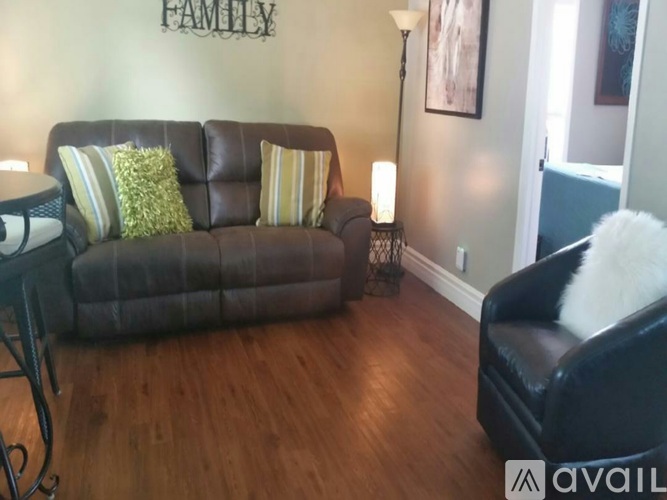 A living room with a brown couch and a black chair.