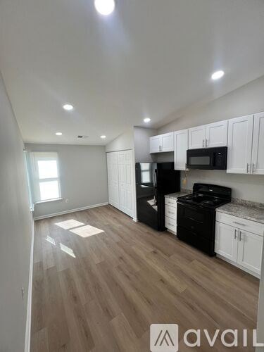A kitchen with black appliances and white cabinets.