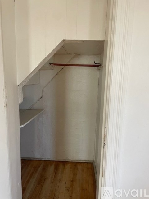 A white wall with a pipe and a white shelf.