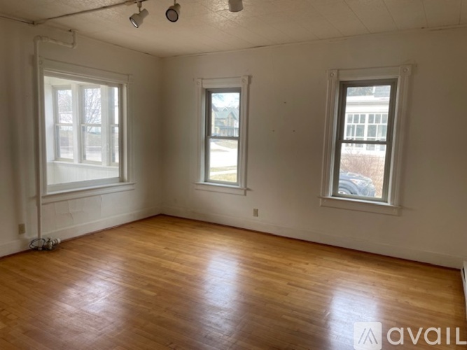 Empty room with wooden floors and two windows.