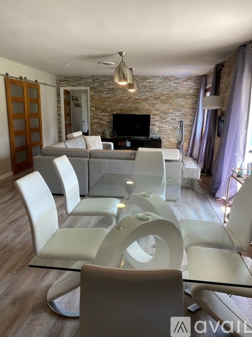 A modern living room with a glass table and white chairs.