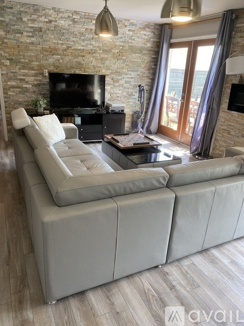 A modern living room with a grey sofa and a stone wall.