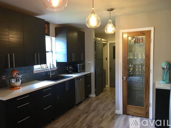 A kitchen with black cabinets and a wooden door.