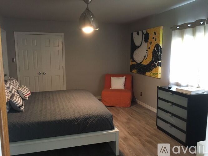 A bedroom with a bed, dresser, and a painting on the wall.
