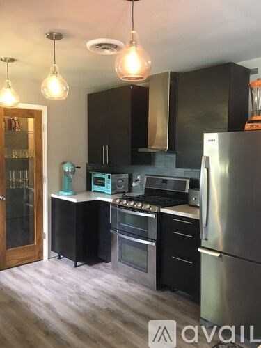 A kitchen with a stainless steel refrigerator and black cabinets.