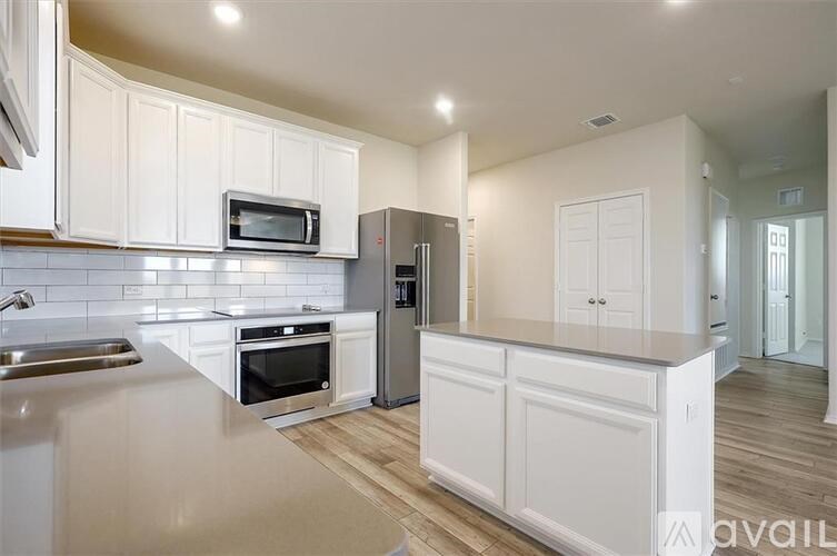 A kitchen with white cabinets and a stainless steel refrigerator.