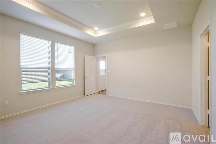 A spacious room with a carpeted floor and two windows.