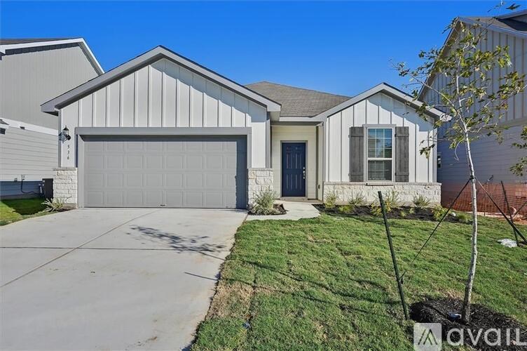 A house with a grey garage door and a tree in front.
