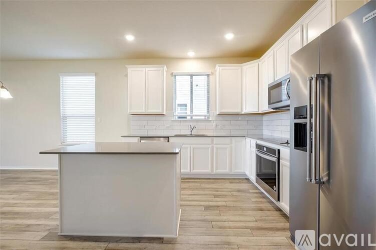 A kitchen with a white island and stainless steel appliances.
