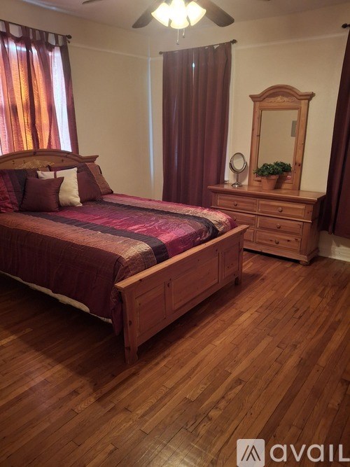 A bedroom with a bed, dresser, mirror, and a ceiling fan.