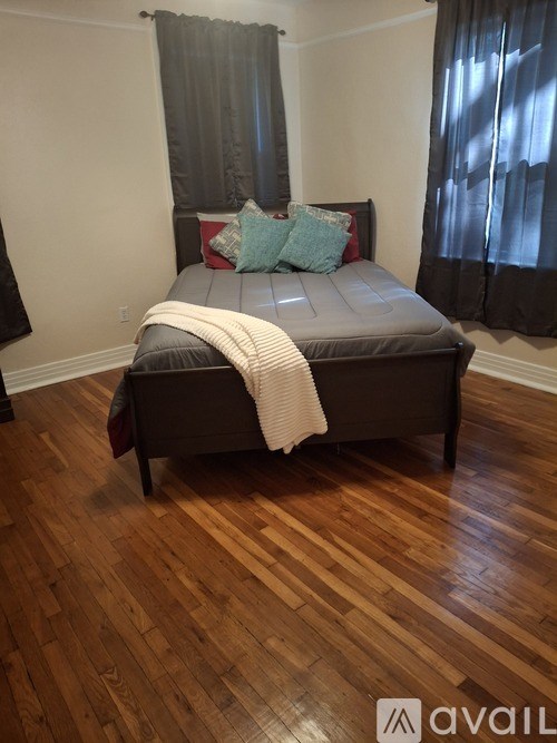 A bedroom with a bed and wooden floors.
