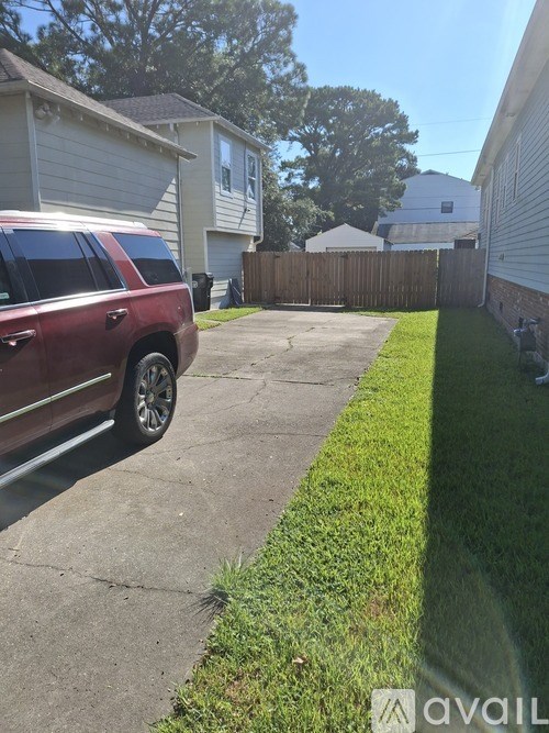 A red SUV is parked on a driveway in front of a house.