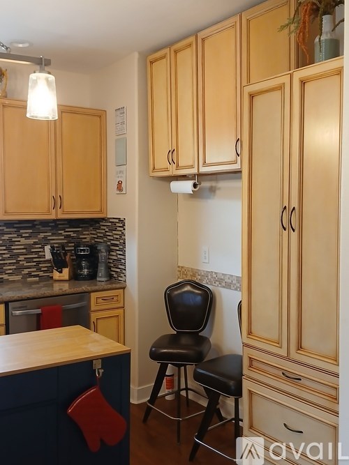 A kitchen with wooden cabinets and a black chair.