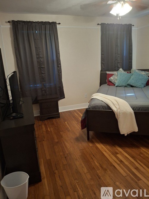 A bedroom with a bed, a television, and a trash can.