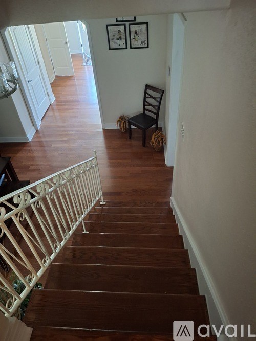 A staircase with a wooden handrail and wooden steps leading to a hallway.