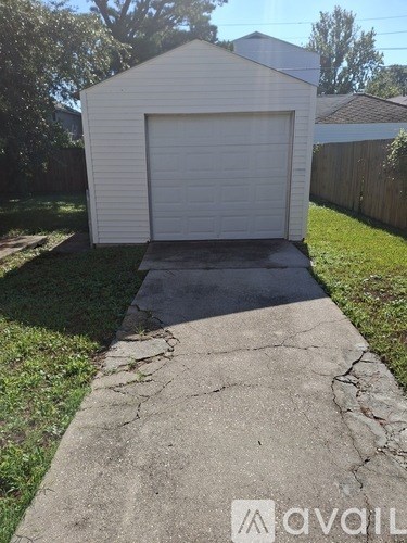 A white garage with a closed white door and a concrete driveway.