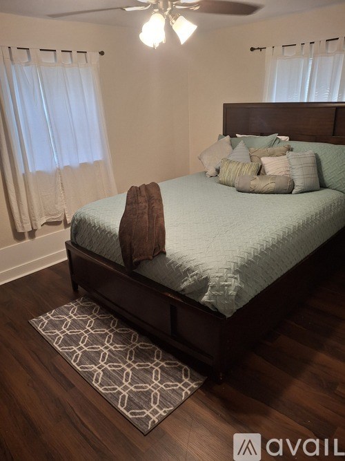 A bedroom with a bed, pillows, and a ceiling fan.