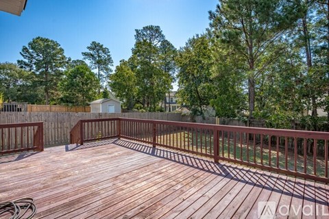 A wooden deck with a railing and trees in the background.